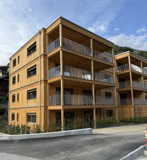 Mehrfamilienhaus in moderner Holzbauweise mit vier Geschossen, grosszügigen Balkonen und Holzfassade.