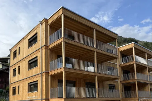 Mehrfamilienhaus in moderner Holzbauweise mit vier Geschossen, grosszügigen Balkonen und Holzfassade.